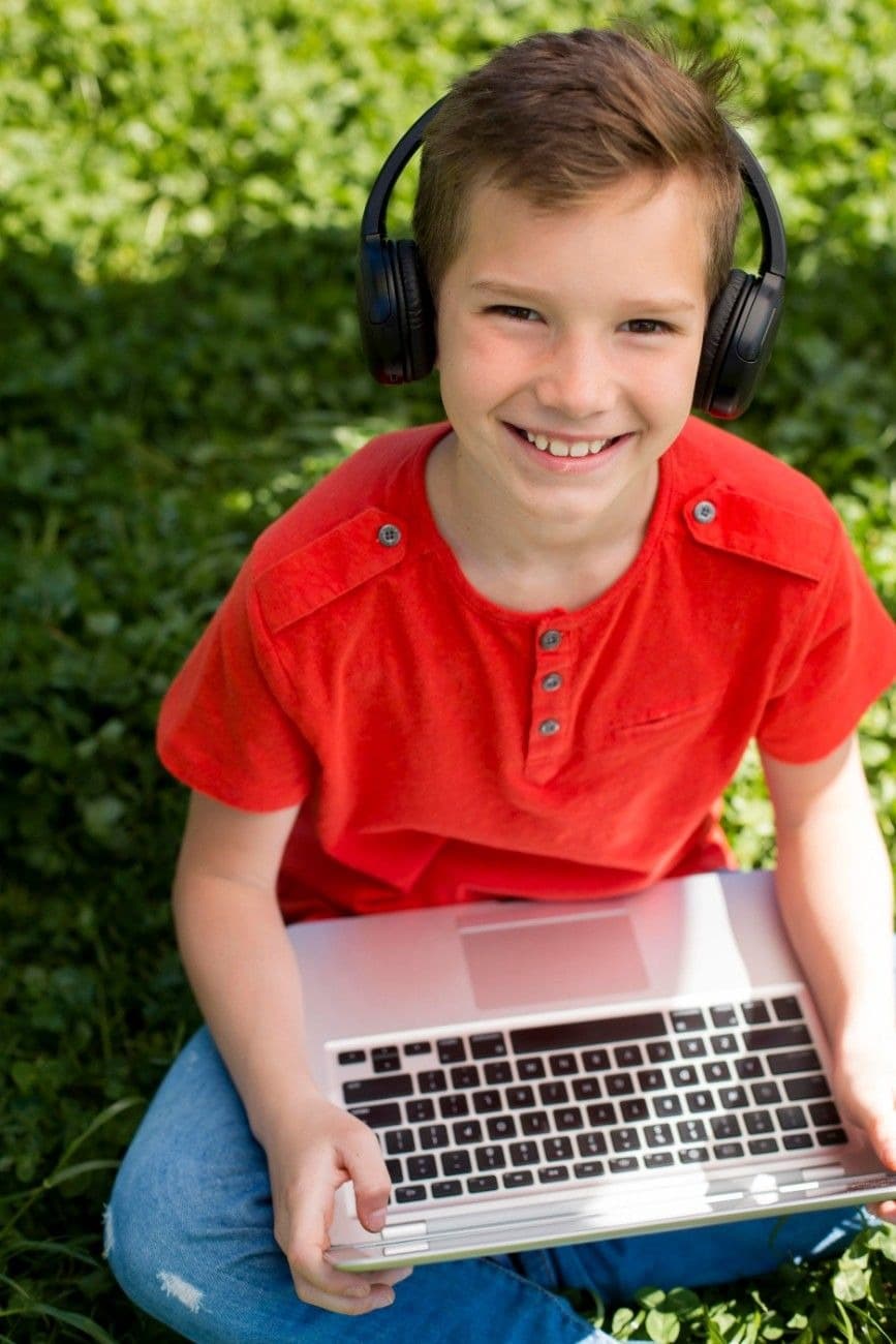 Boy with headphones smiling with a laptop during an online lesson