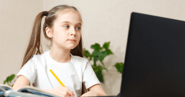 A young girl with pencil in hand thinking through a question at her laptop