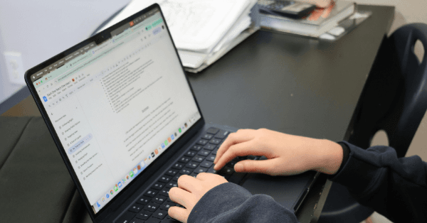 A student's hands typing on a laptop showing an online revision checklist