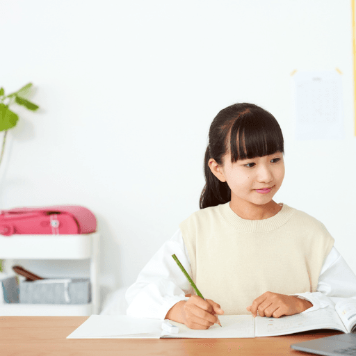 Student practising for the ISEB Pre-Test with a workbook and laptop at her desk