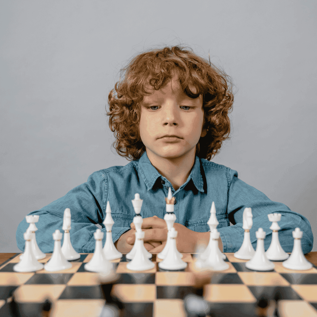A young boy studying his white chess pieces before the game begins