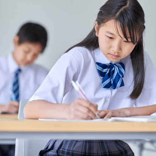 Students in school uniform sitting a written reasoning assessment in a classroom